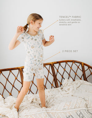 girl standing on couch wearing Meadow Lane Kids Heirloom Homestead kids short sleeve and shorts kids pajamas