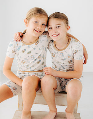 two girls wearing Meadow Lane Kids Heirloom Homestead TENCEL kids short sleeve shirt and shorts pajamas