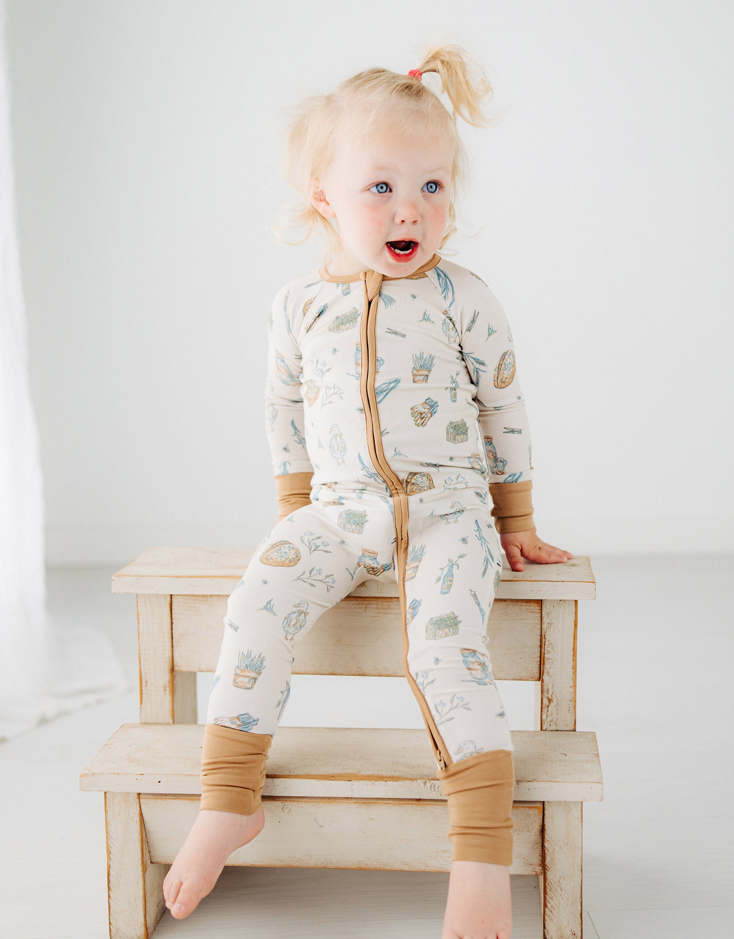 little girl sitting on a step in Meadow Lane Kids Heirloom Homestead TENCEL toddler sleeper